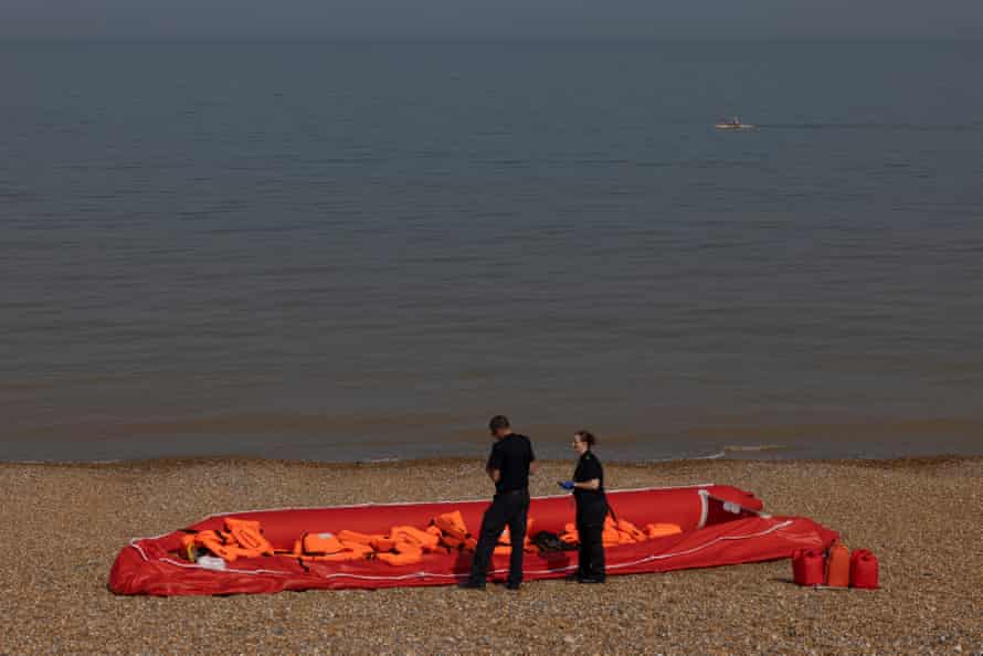 Des agents des forces frontalières inspectent un canot pneumatique, jeté sur une plage après avoir été utilisé par des migrants pour traverser la Manche, à Walmer