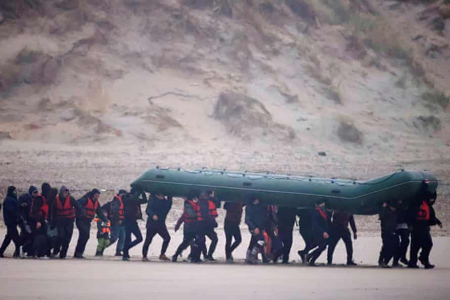 Un groupe de migrants court sur la plage avec un canot pneumatique près de Wimereux, France