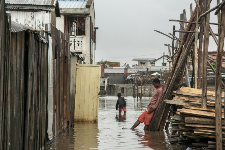 Des habitants marchent dans l'eau que a inondé le quartier d'Antohomadinika, à Antananarivo, le 24 janvier 2022, après le passage de la tempête tropicale Ana (AFP - RIJASOLO)