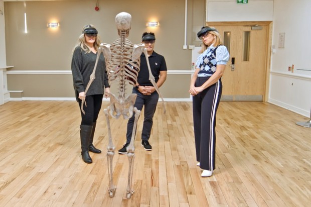 La patiente Melina, le Dr Purkayasthar et Kate Garraway utilisent des casques de réalité augmentée pour regarder une représentation 3D du squelette de Melina © BBC / Remarkable TV La patiente Melina, le Dr Purkayasthar et Kate Garraway utilisent des casques de réalité augmentée pour regarder une représentation 3D du squelette de Melina