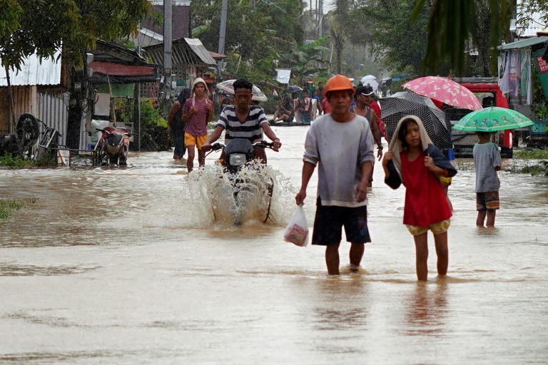 Des passants dans une rue inondée d'Abuyog, aux Philippines, after the passage of the tempête Megi, on April 11, 2022 (AFP - Bobbie ALOTA)