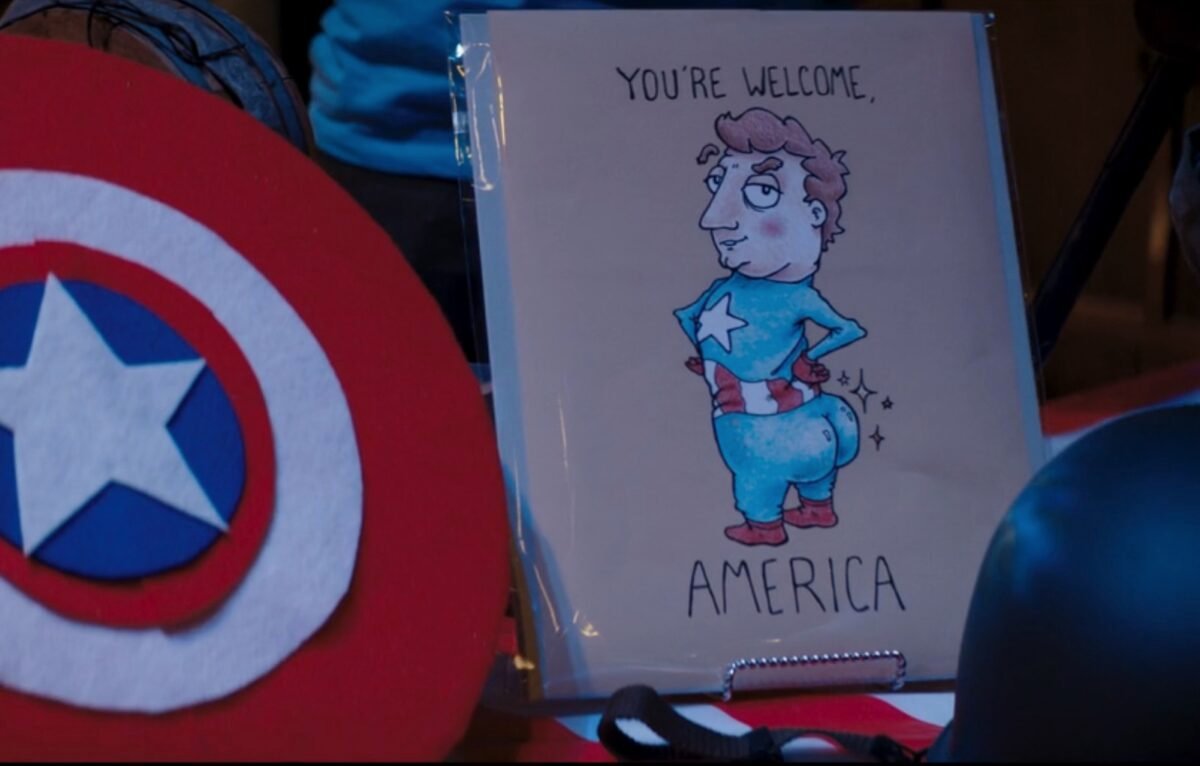 Je veux entendre les interviews de podcast de Scott Lang de 'Ms. Merveille' 4 Une carte de vœux avec un dessin animé de Captain America qui sort les fesses, avec les mots "De rien, Amérique." À côté de lui se trouve un bouclier de feutre.