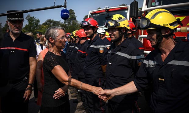 La première ministre française, Elisabeth Borne (au centre), salue les pompiers alors qu'elle visite le site d'un incendie de forêt à Hostens, dans le sud-ouest de la France