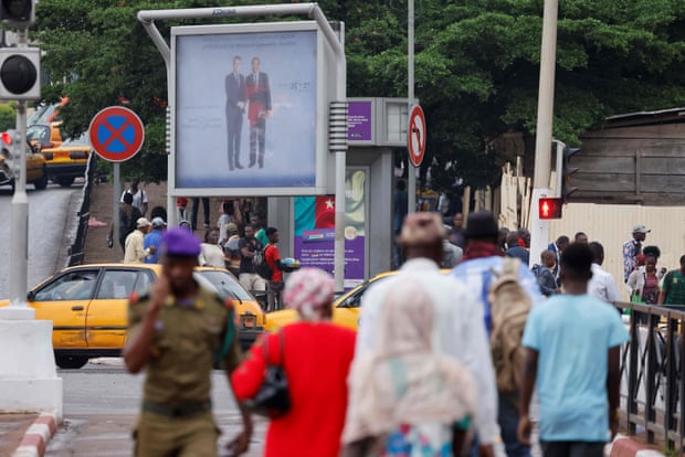 Les gens de Yaoundé passent devant une affiche de Biya et Macron