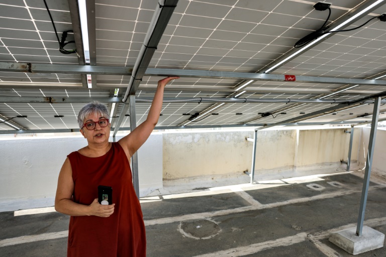 Zeina Sayeh, une habitante de Beyrouth, montre les panneaux solaires installés au-dessus de son appartement, le 29 août 2022. (AFP - JOSEPH EID)