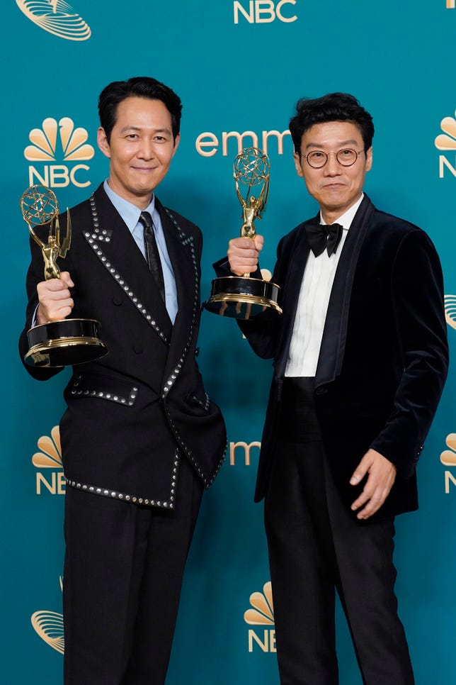 Comment Netflix, 'Squid Game' et le 'K-Wave' coréen ont brisé la barrière des Emmys 3 Les deux hommes portant des costumes cravate noire tiennent leurs Emmys à hauteur de poitrine.