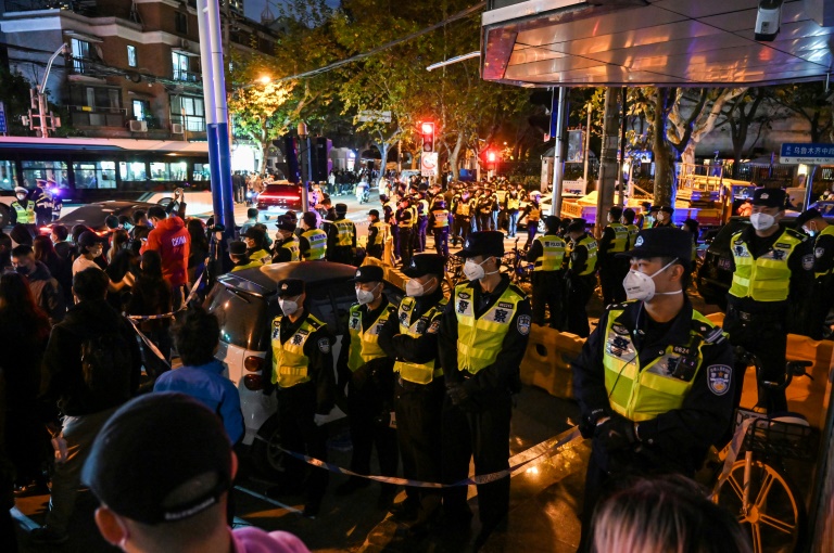 Des policiers bloquent la rue Ulumutsi, le nom chinois de la ville d'Urumqi, lors d'une manifestation contre la politique anti-covid du gouvernement chinois, le 27 novembre 2022 à Shanghai (AFP - Hector RETAMAL)
