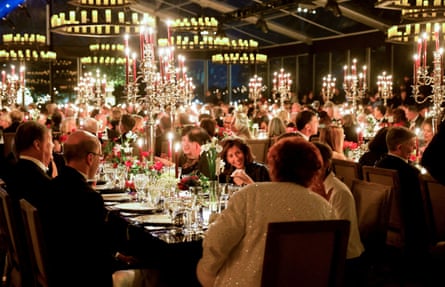Les invités de la Maison Blanche sont assis à des tables dans une tente sur la pelouse sud.  Plusieurs grands candélabres s'élèvent de chaque table
