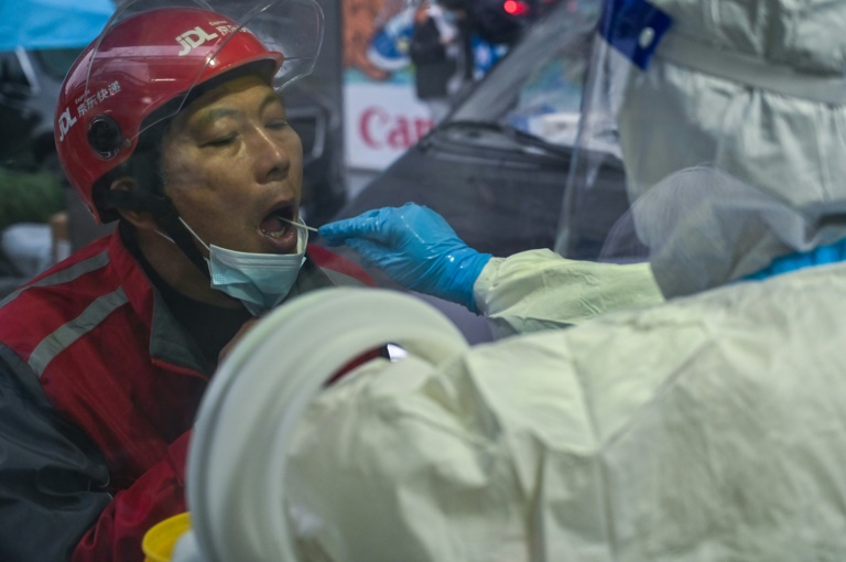 Un agent de santé prélève un échantillon sur écouvillon d'une femme pour un test de dépistage du coronavirus à Shanghai (AFP - Hector RETAMAL)