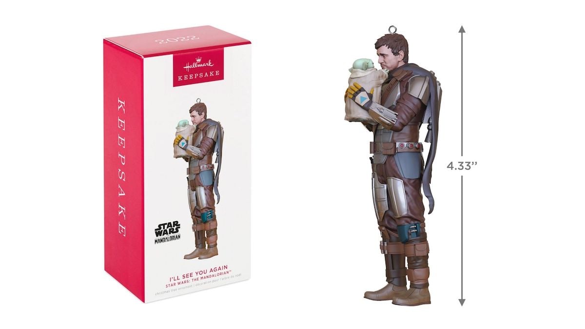 Les meilleurs cadeaux pour les fans de "Star Wars" en 2022 | The Mary Sue 13 Une décoration de sapin de Noël représentant Din Djarin tenant Grogu à côté de la boîte dans laquelle il est emballé.