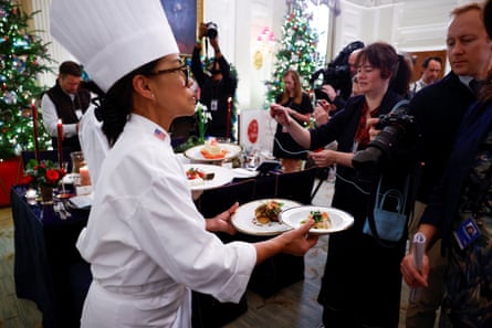 Un chef tient plusieurs assiettes dans ses mains pendant que des membres des médias prennent des photos.
