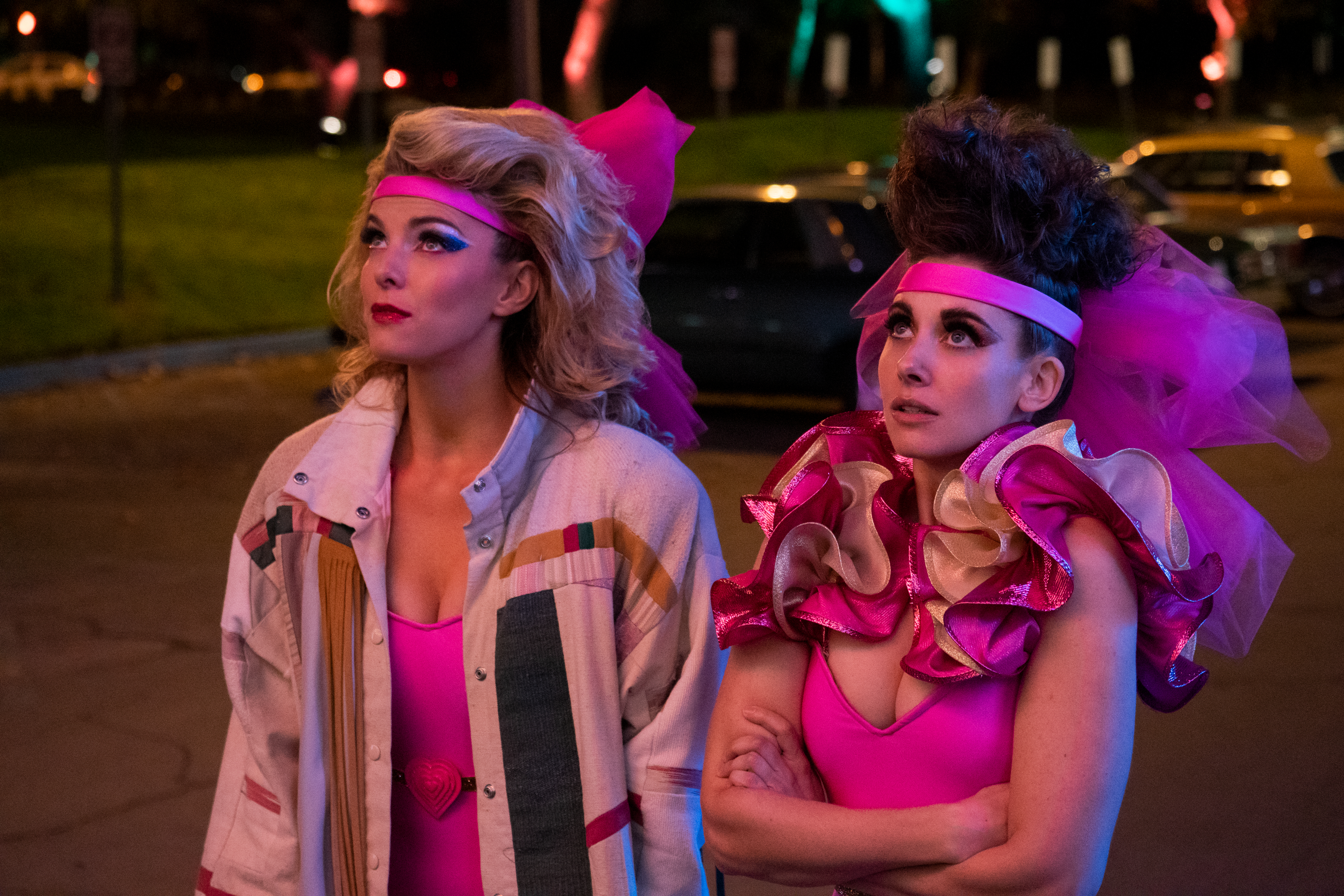 Comment je réparerais Netflix en 2023 3 (De gauche à droite) Debbie (jouée par Betty Gilpin) et Ruth (jouée par Alison Brie) regardent le ciel en portant des tenues rose fluo dans la série GLOW de Netflix.