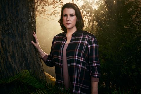 Yellowjackets - Melanie Lynskey en tant que Shauna la star des yellowjackets, melanie lynskey, en personnage de shauna, se tient dans une forêt avec sa main droite posée sur un tronc d'arbre