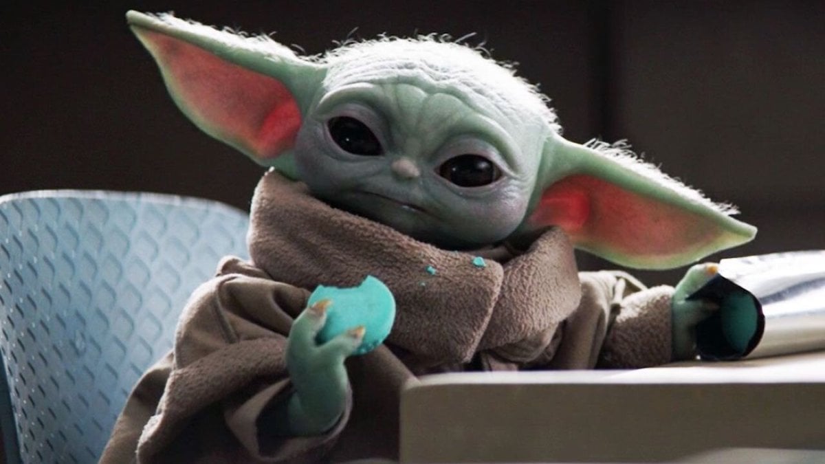 Les meilleurs cadeaux pour les fans de "Star Wars" en 2022 | The Mary Sue 3 Gros plan de Grogu de The Mandalorian assis sur une chaise à une table, mangeant des macarons bleus
