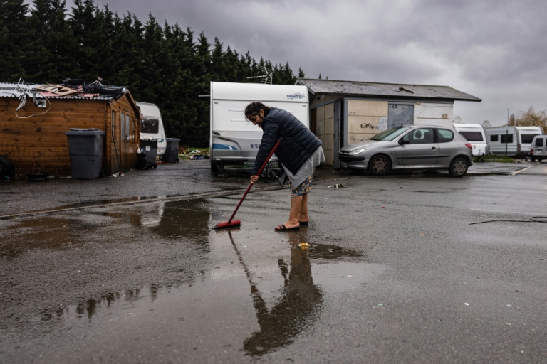 Un membre de la communauté des voyageurs balaie devant sa caravane à Ronchin, dans le nord de la France, le 16 janvier 2023. (AFP - Sameer Al-DUMI)