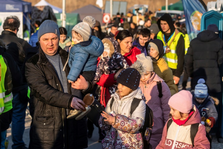 Des réfugiés attendent qu'un bus poursuive son voyage après avoir traversé la frontière avec l'Ukraine à Medyka, dans le sud-est de la Pologne, le 19 mars 2022. (AFP - Wojtek RADWANSKI)