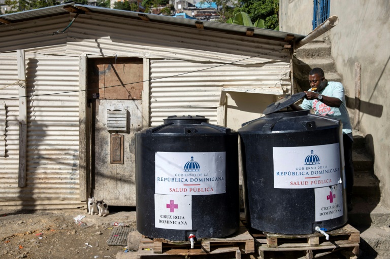 Un employé de la compagnie nationale des eaux remplit des conteneurs placés par le ministère de la Santé à La Sursa, Saint-Domingue, le 9 février 2023. (AFP - Erika SANTELICES)